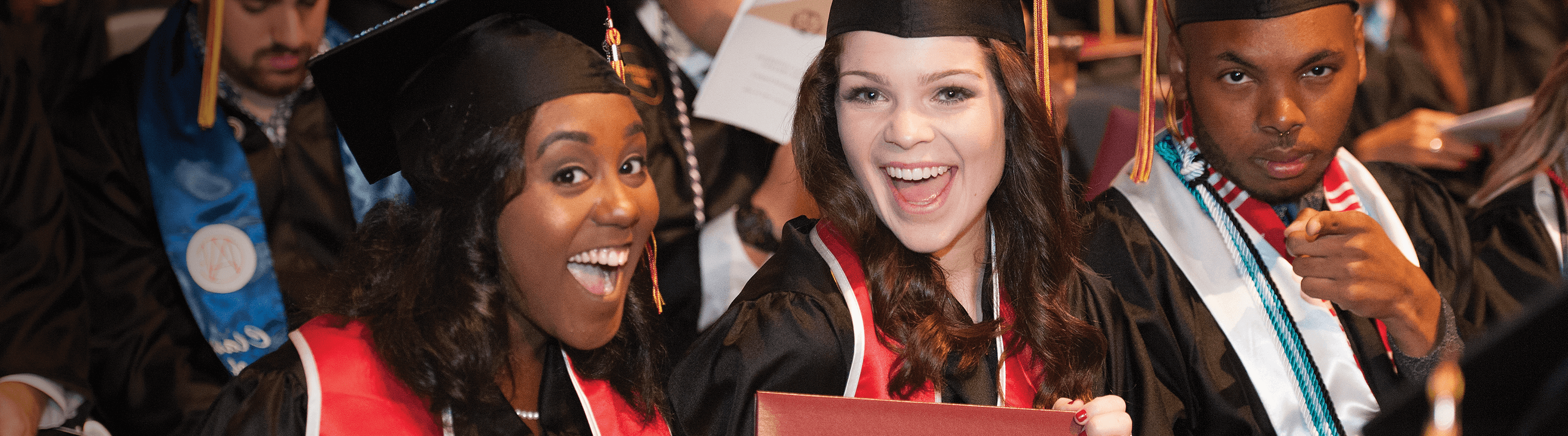 Smiling students graduating in cap and gown